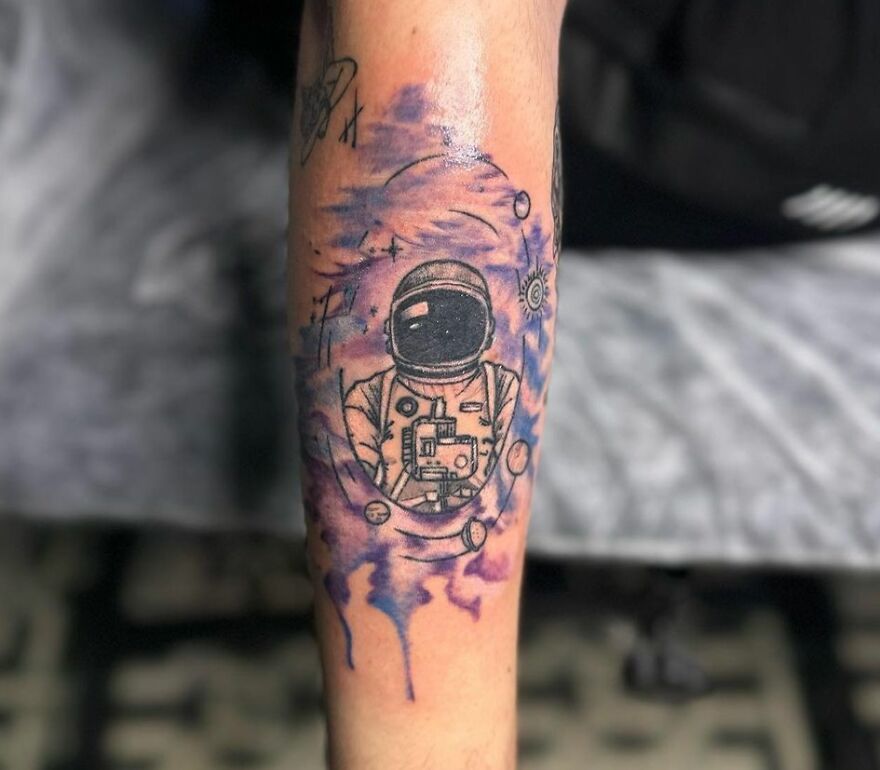 Astronaut in space with planets floating around forearm tattoo