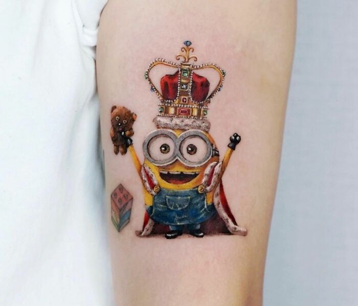 Realistic Minion with a crown arm tattoo