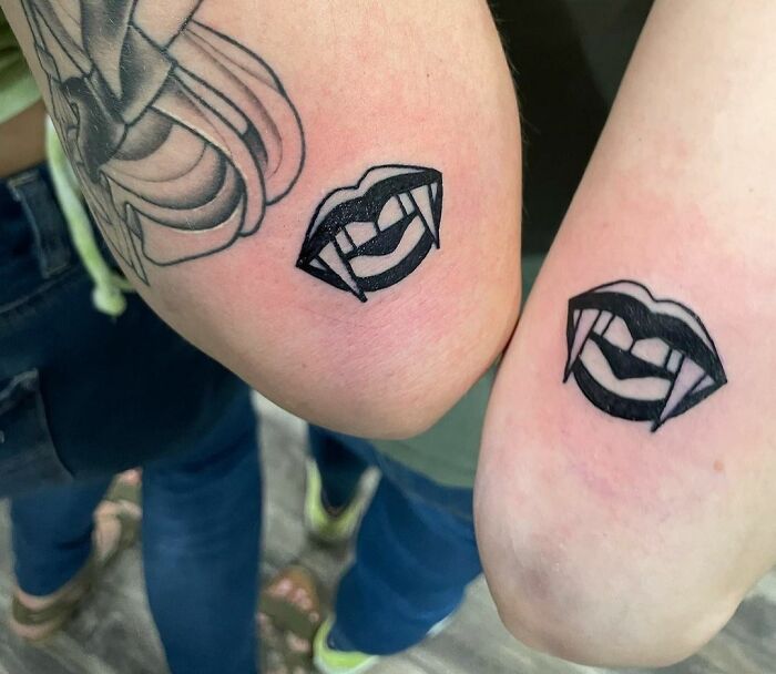 Matching vampire lips with fangs arm tattoos