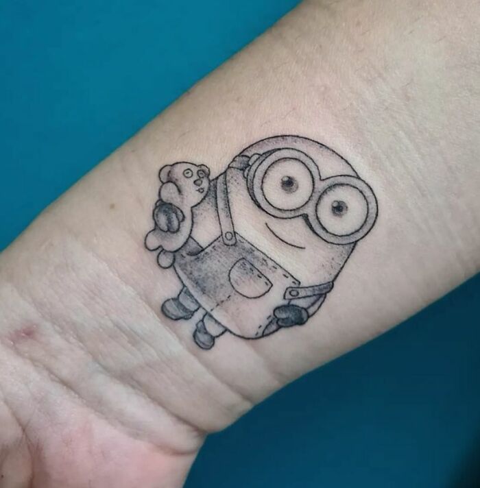 Minion holding a teddy bear wrist tattoo