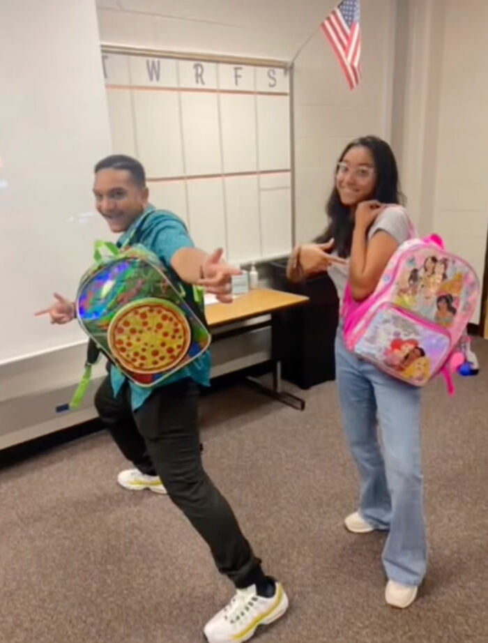 High school seniors pose with colorful kindergarten backpacks in a classroom setting. High school seniors pose with colorful kindergarten backpacks in a classroom setting.