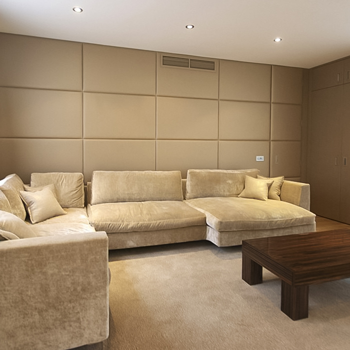Living room with light brown fabric wall panels, large sofa and wooden table