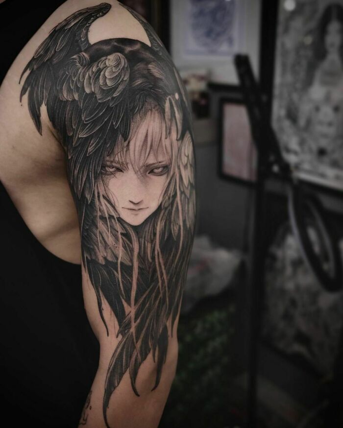 Intricate gothic tattoo featuring a dark-haired figure with crow elements on an arm.