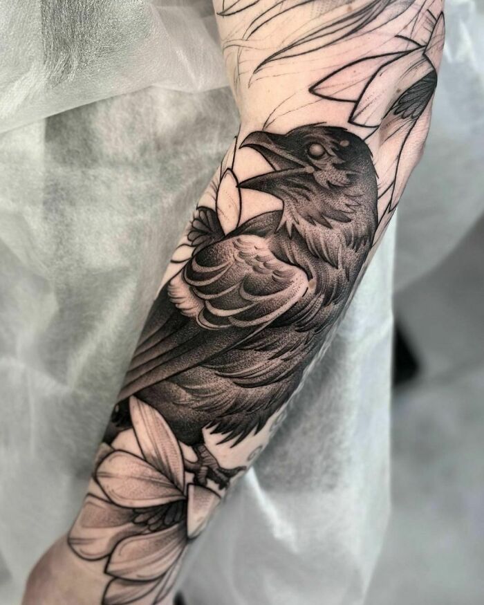 Close-up of a gothic tattoo featuring a detailed crow design on an arm.