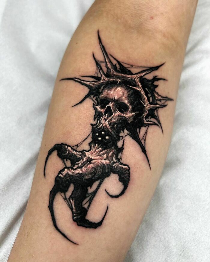 Gothic tattoo featuring a detailed skull with c*****d textures and sharp edges on a forearm.