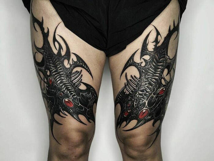 Dark Symmetrical Thigh tattoos with red eyes