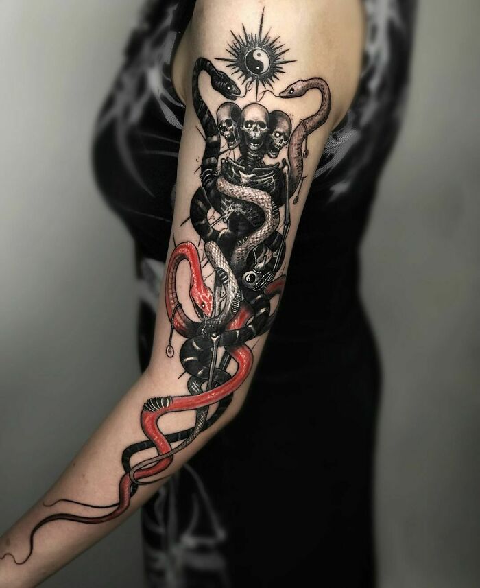 Gothic tattoo with snakes and skulls on an arm.