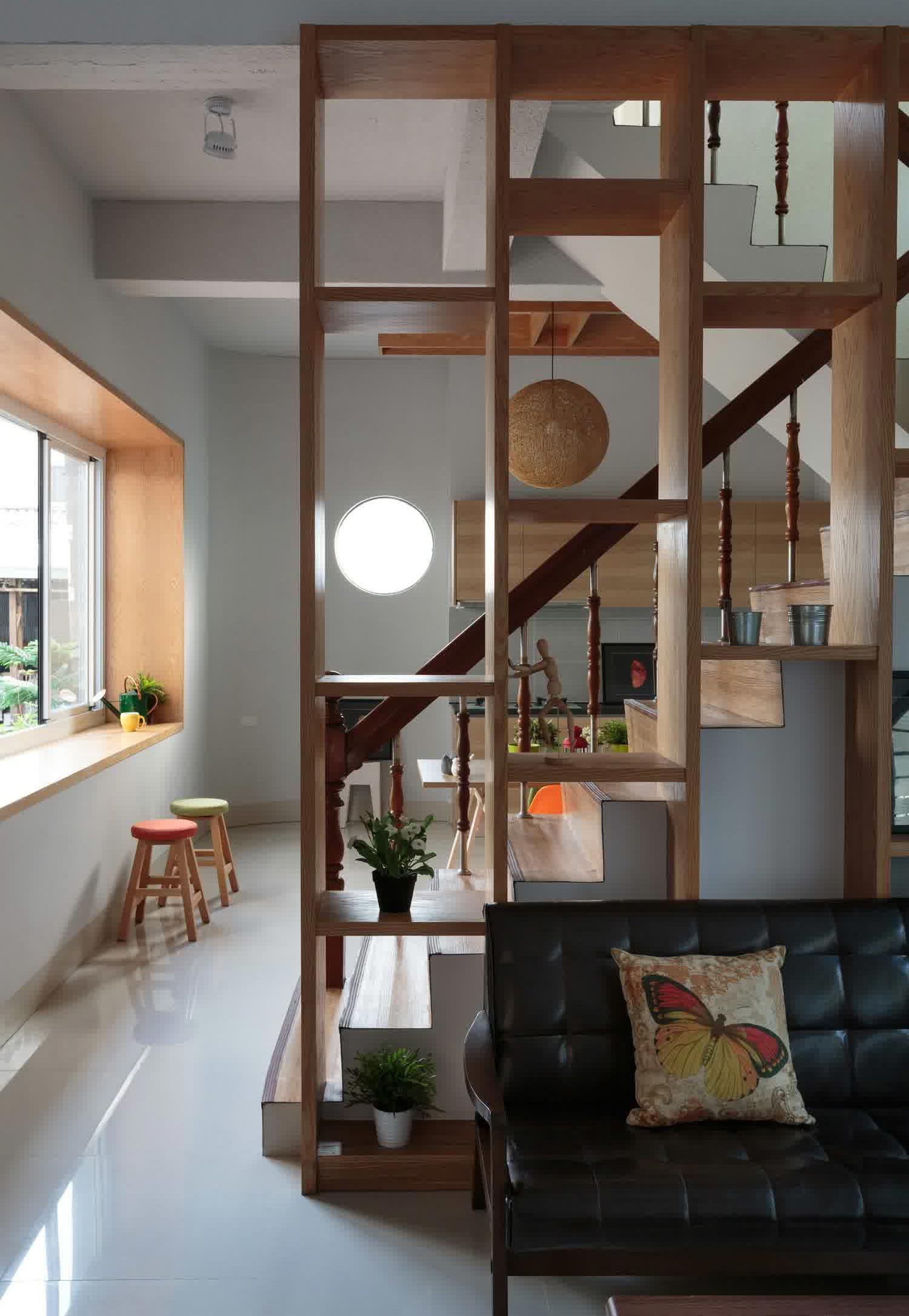 Wooden floor-to-ceiling shelf room divider in an apartment with stairs Wooden floor-to-ceiling shelf room divider in an apartment with stairs