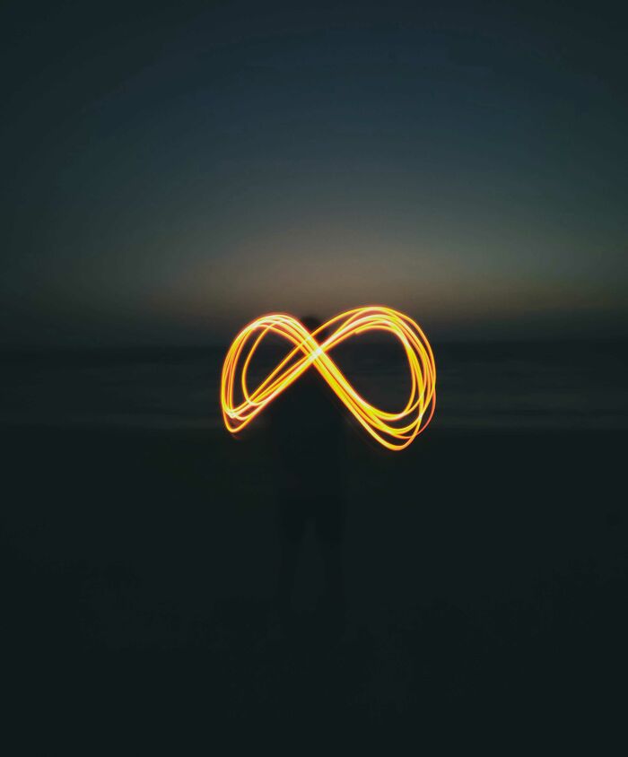 A person draws with sparkling light the symbol of infinity at night