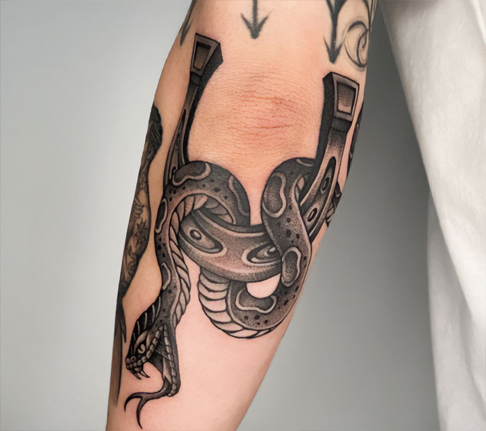 Snake and horseshoe elbow tattoo