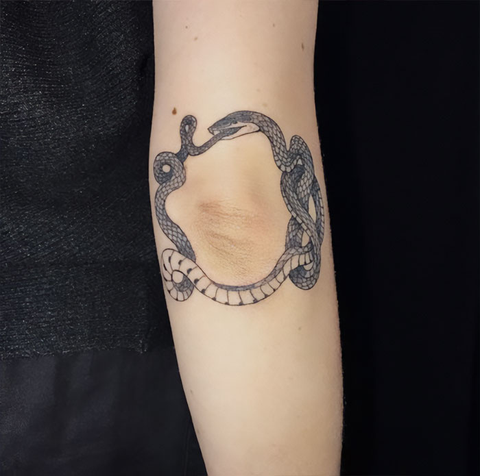 Round snake eating itself elbow tattoo