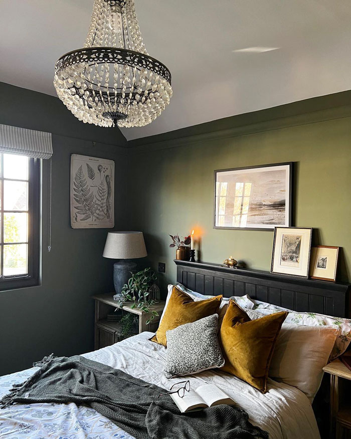 A bedroom with green walls and a classy chandelier on the ceiling