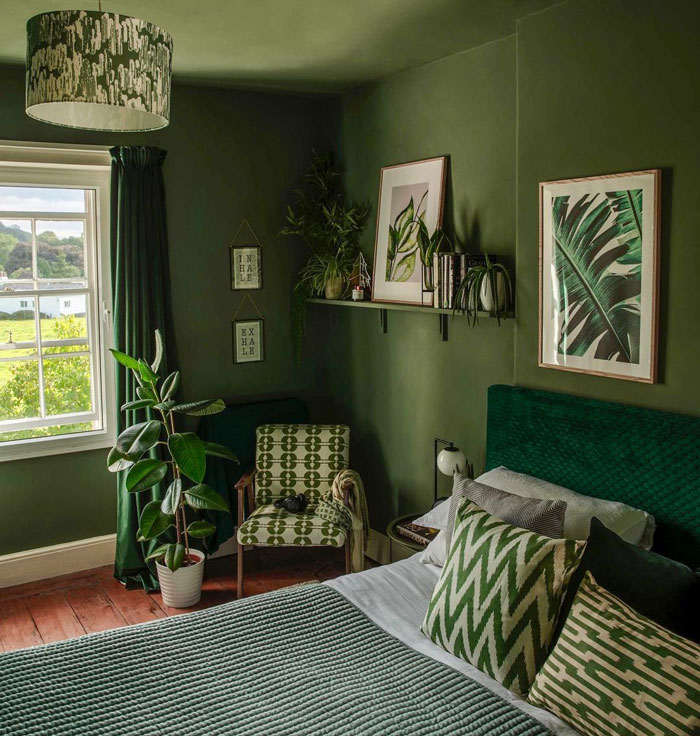 Bedroom with green tints all over, pictures of plants on the walls and flowers around