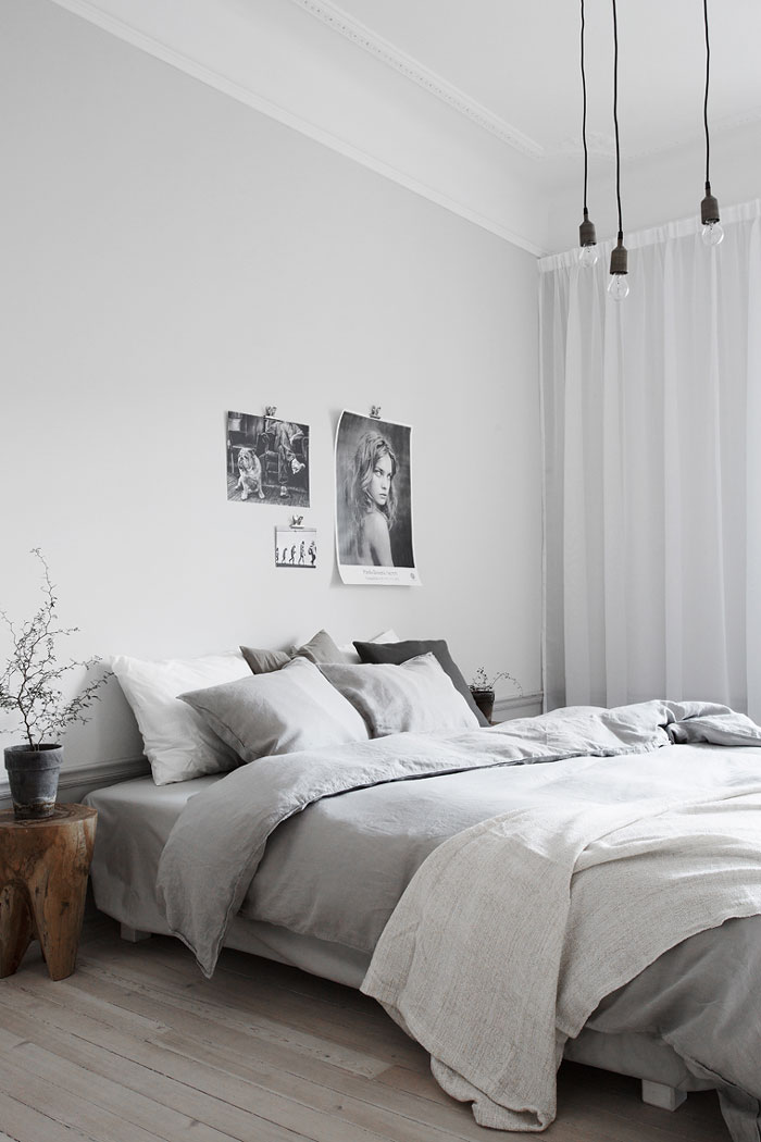 Monochromatic gray room with black and white pictures on the wall and grey bedding