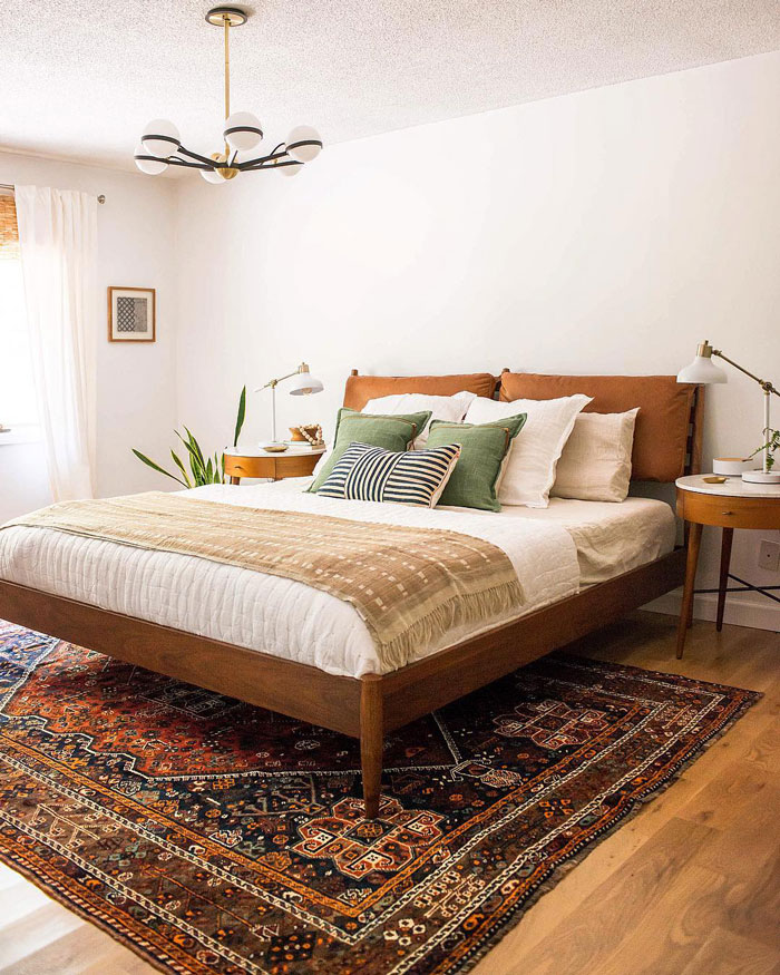 Cozy and light bedroom with wooden bed platform and Persian style carpet under bed