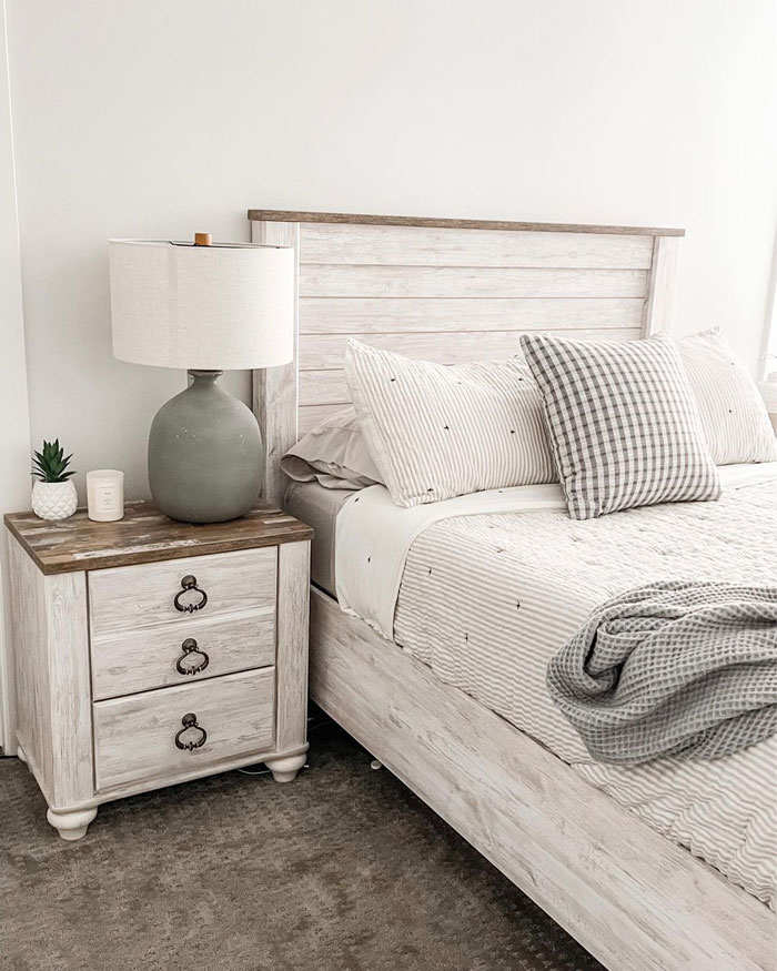 Light bedroom with whitewash furniture, gray lamp on the bedside table and white bedding