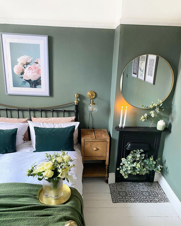 Room with green walls and picture of flowers and mirror on them