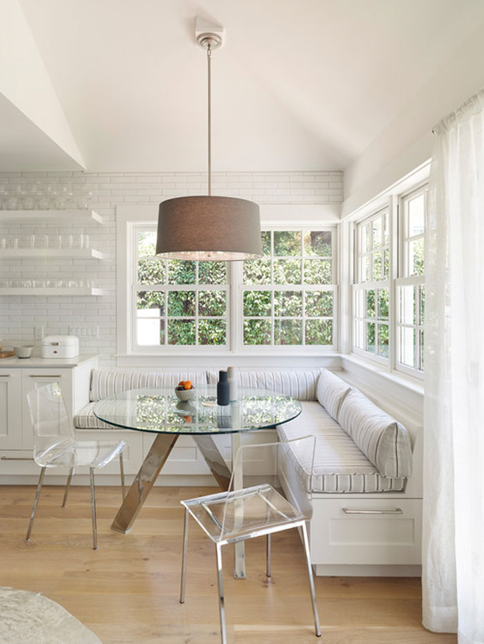 White interior cozy breakfast nook with a glass table and chairs and storage space