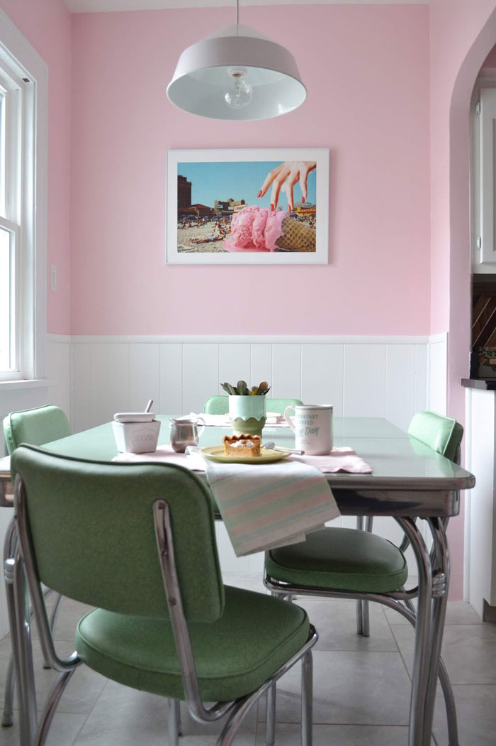 Retro style breakfast nook with light pink walls, green table and chairs with metal details