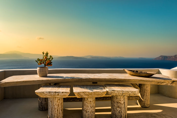 A wooden bench and chairs overlooking the sky and mountains