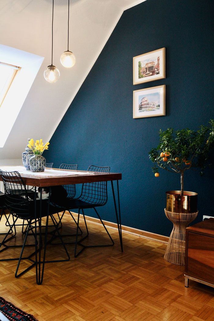 A bright blue breakfast nook with colorful plants and black metal chairs