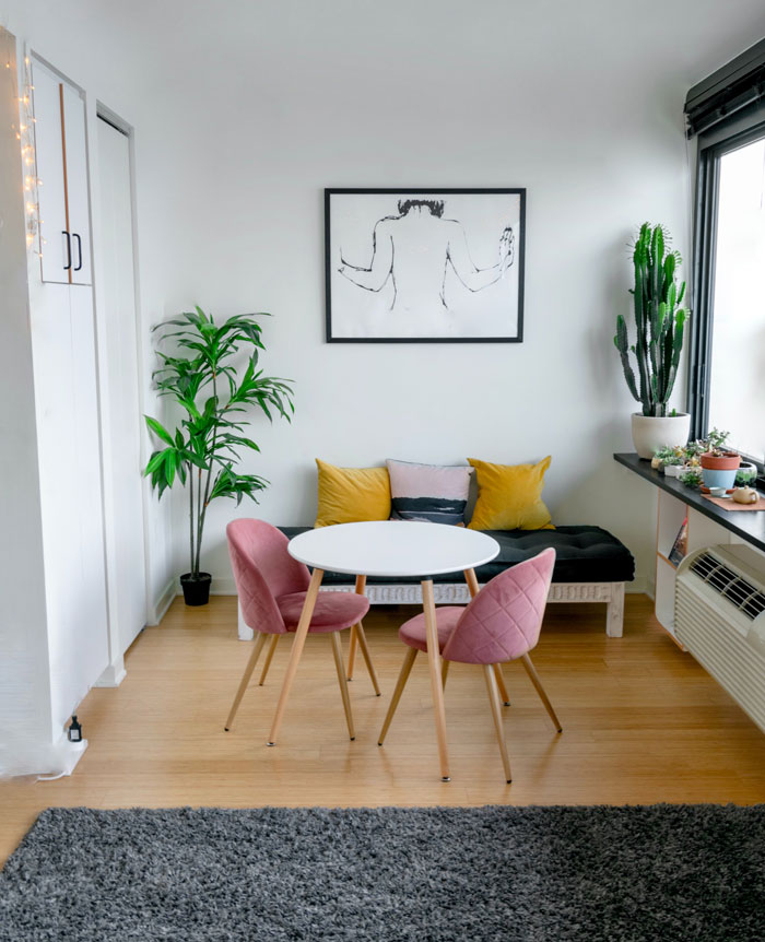 Two pink chairs in a cozy minimalistic breakfast nook next to a couch