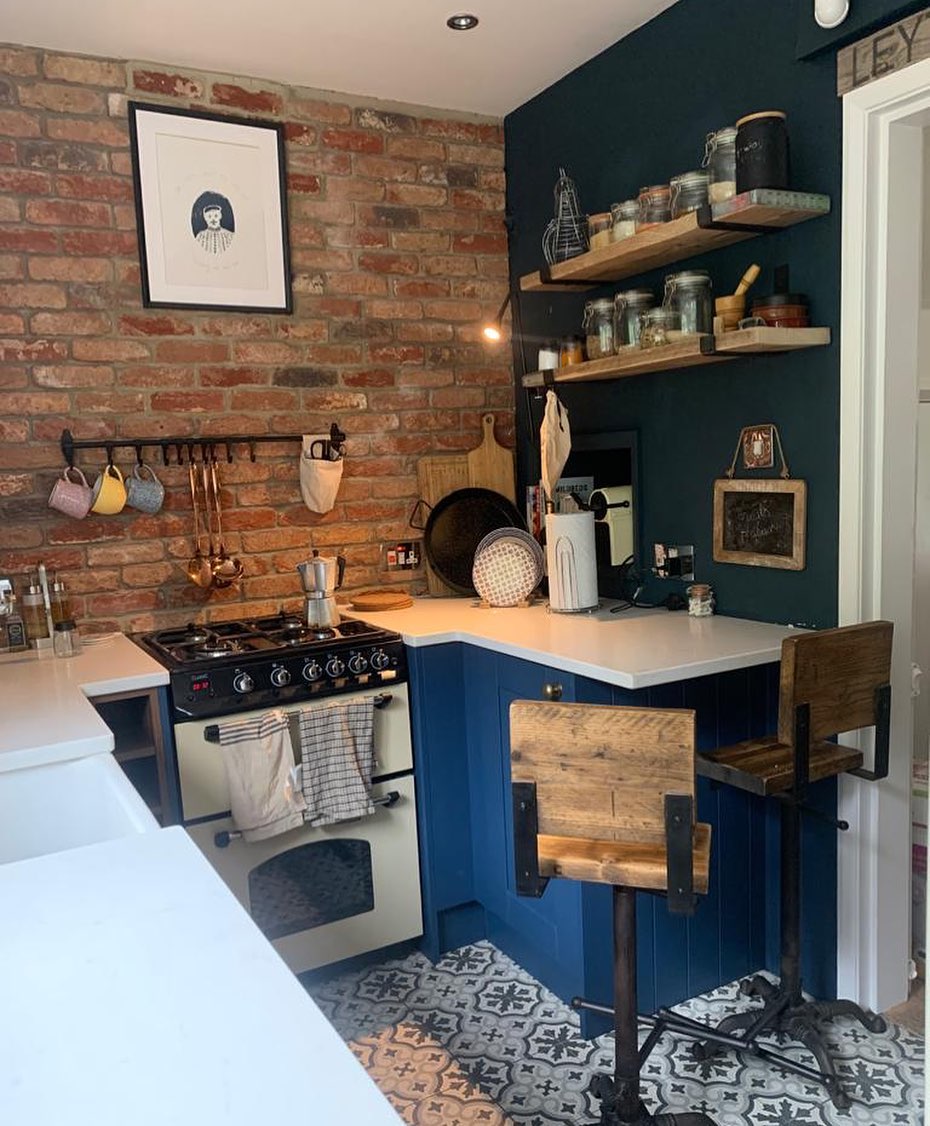 Small kitchen with blue cabinets and exposed brick wall design 