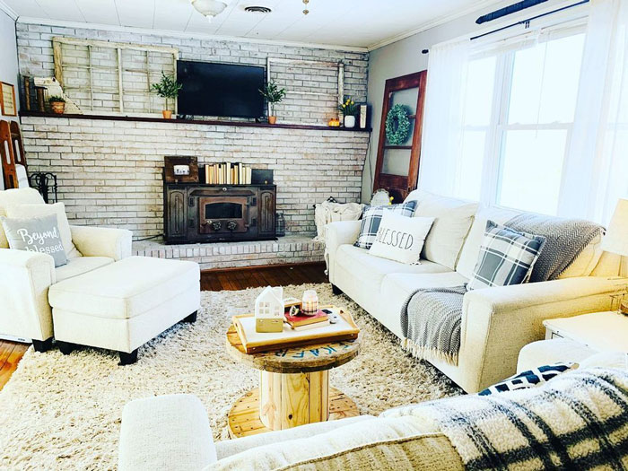 White wash brick wall room with sofas and armchair, fireplace and carpet on the floor 