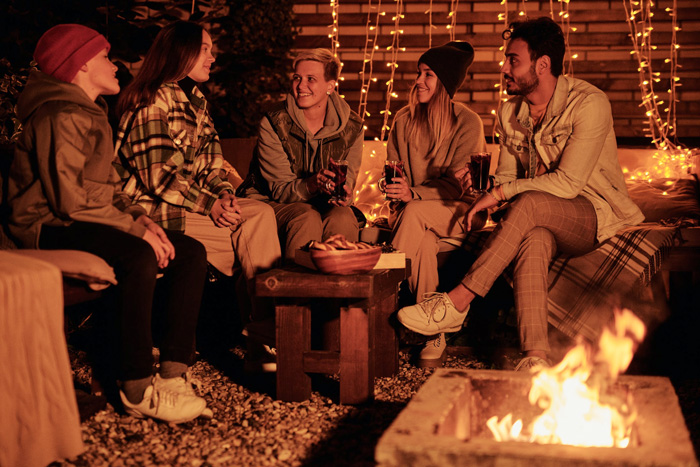 Group of friends sitting by a bonfire at night-time