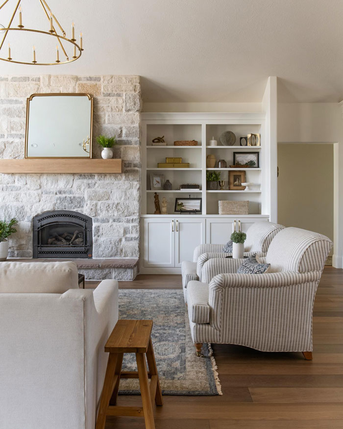 White creamy interior farmhouse with striped sofas and white cupboard and fireplace