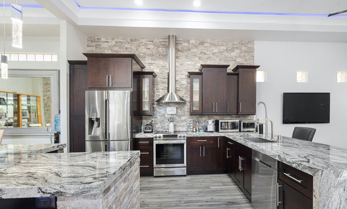 Marble kitchen with silver French-door refrigerator and brown cupboards