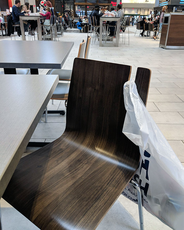 Estas sillas en la zona de restaurantes del centro comercial tienen un hueco para colgar las bolsas con las compras