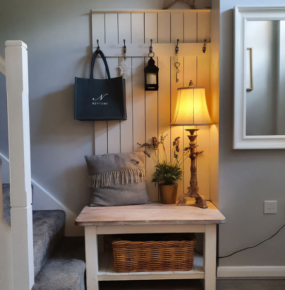 A small white wooden hall tree with a pillow, plant, lamp, and other items on it A small white wooden hall tree with a pillow, plant, lamp, and other items on it