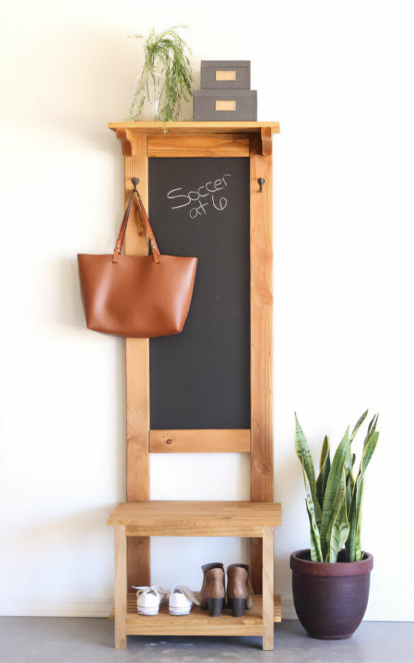 A wooden hall tree with a blackboard and a bag hanging from it A wooden hall tree with a blackboard and a bag hanging from it