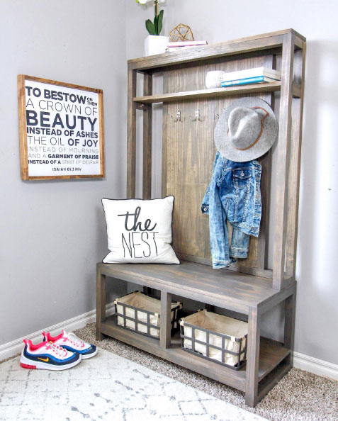 A brown hall tree with a hat, jacket, books, and pillow on it A brown hall tree with a hat, jacket, books, and pillow on it
