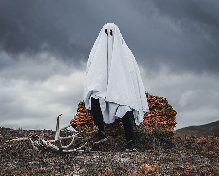 Man wearing ghost costume and sitting