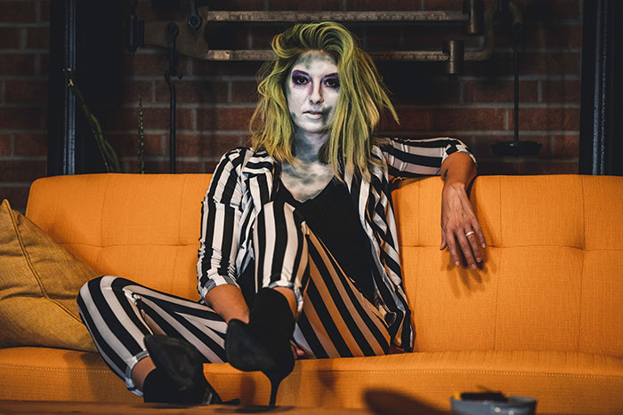 Woman wearing make up and costume of Joker and sitting