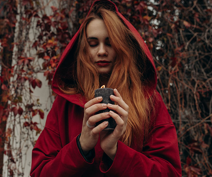 Woman wearing red hoodie and holding black candle