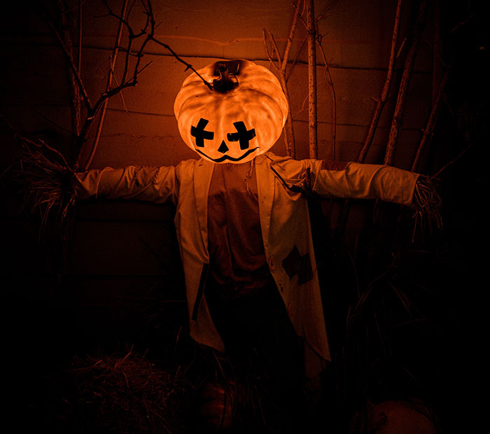 Scarecrow wearing pumpkin head and white coat