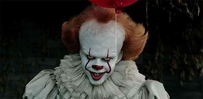 Pennywise smiling and holding red balloon