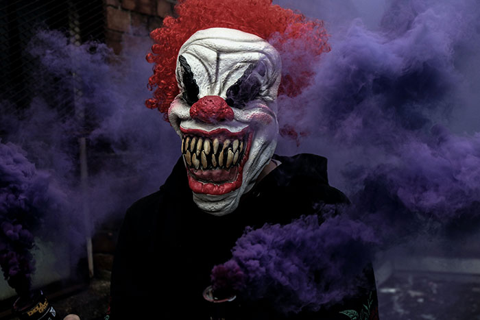Man wearing black hoodie and clown mask