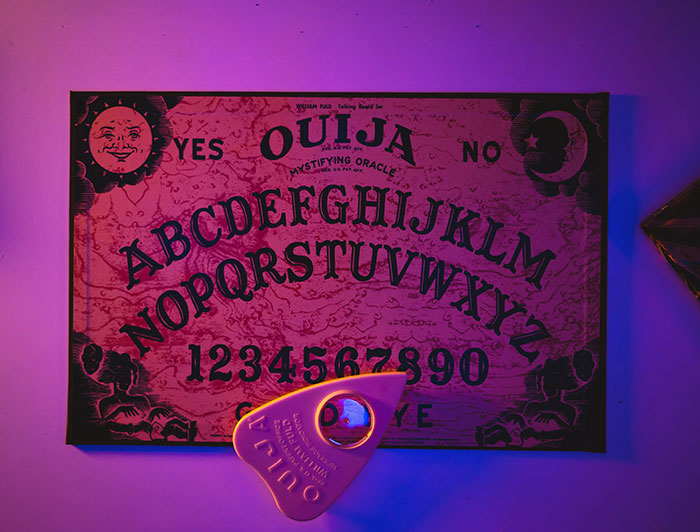 Ouija board at the table with purple background light