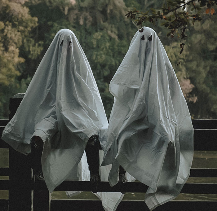 Mans wearing ghost costumes and sitting