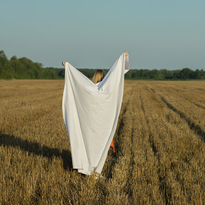 Woman holding white sheet in the field
