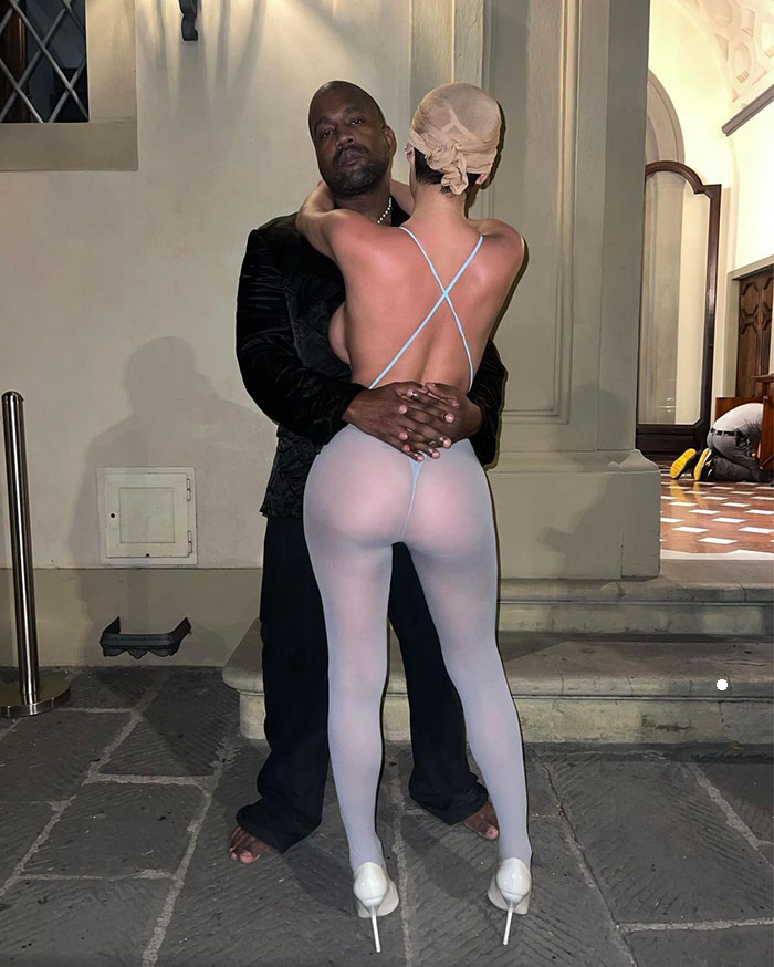 Bianca Censori wearing revealing outfit with Kanye West, standing together in front of a building. Bianca Censori wearing revealing outfit with Kanye West, standing together in front of a building.