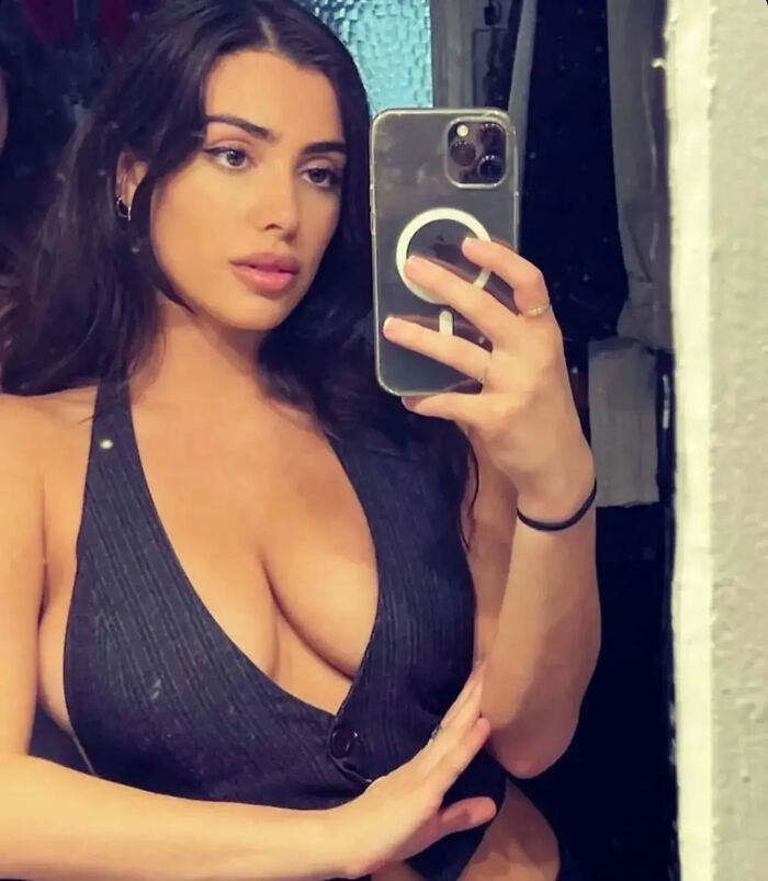 Woman takes a mirror selfie wearing a revealing black top. Woman takes a mirror selfie wearing a revealing black top.