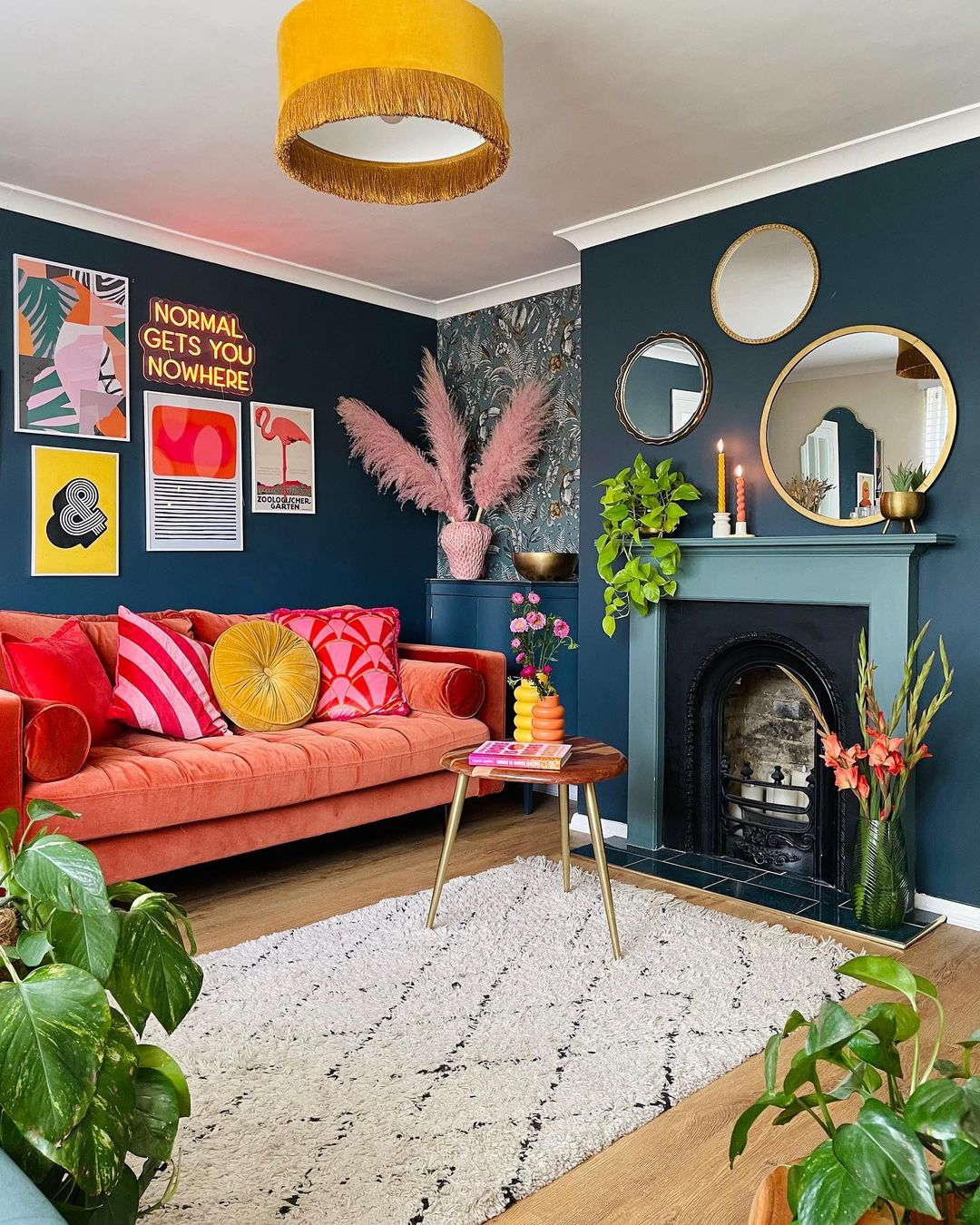 Colorful living room ideas featuring an orange velvet sofa, dark blue walls, and a decorative fireplace with mirrors. Colorful living room ideas featuring an orange velvet sofa, dark blue walls, and a decorative fireplace with mirrors.