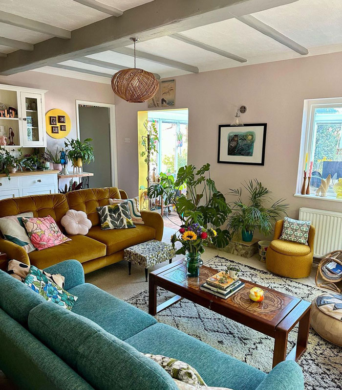 Living room with blue and yellow couches, a coffee table and many plants