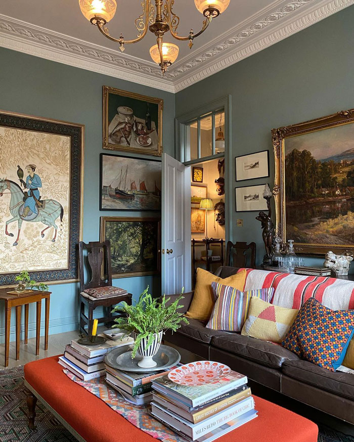 Elegant eclectic living space with vintage style paintings on the walls