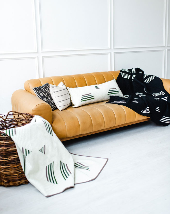 Yellow couch with black and white geometric patterned blankets and cushions